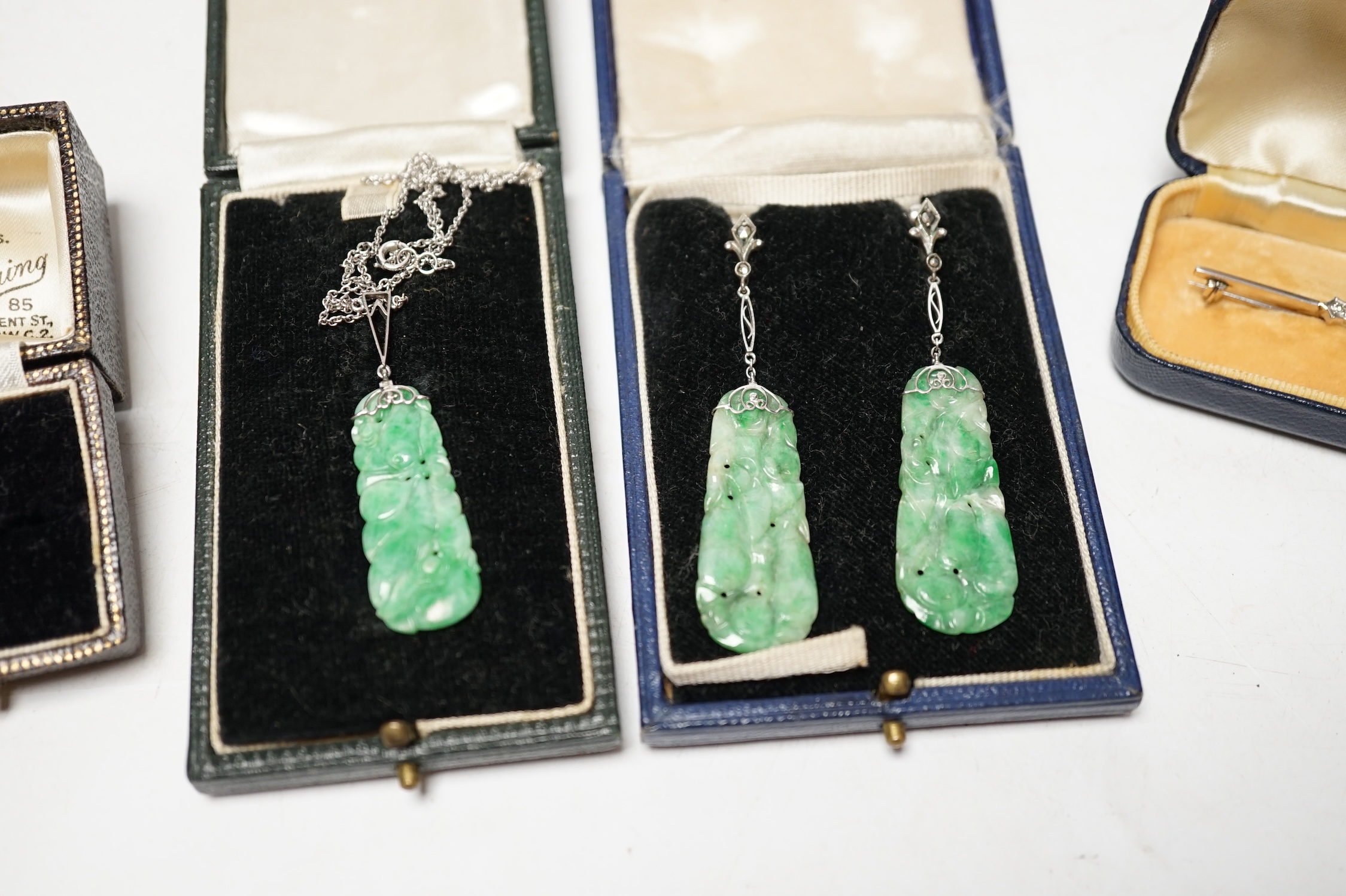 A cased 1930's white metal, single stone carved jade and two stone diamond set bar brooch, 62mm, a similar 9ct and carved jade set ring, a similar cased pair of 935 white metal, jade and marcasite set drop earrings and a